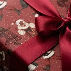 Black Santa luxury Christmas wrapping paper with a burgundy satin bow by Wrapped Studios.
