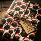 Black Santa Christmas wrapping paper on a gift with twine and Ho Ho Ho tag by Wrapped Studios.