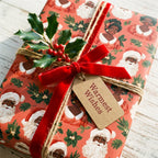 Black Santa Christmas wrapping paper with a red velvet bow and holly by Wrapped Studios.