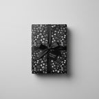 Elegant gift wrapped in floral wrapping paper with a black ribbon and a gift tag.