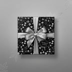 Elegant floral wrapping paper in black and silver with satin bow, luxury gift wrap.