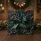 Elegant Christmas gift wrap with silver leaf pattern, dark green ribbon, and "With Love" tag.