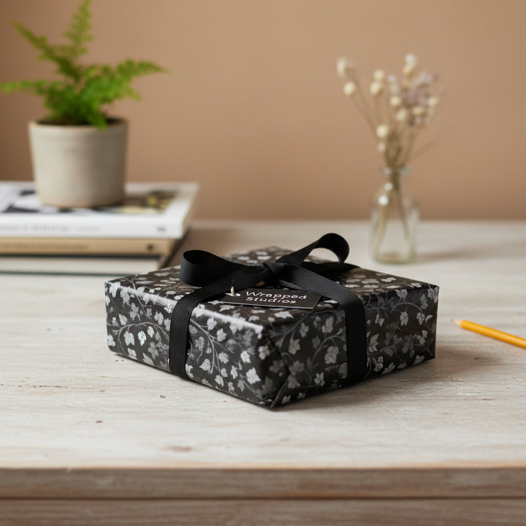 Elegant gift wrapped in black floral wrapping paper with a simple black ribbon.