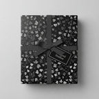 Elegant gift wrapped in black floral wrapping paper with gray ribbon and tag.