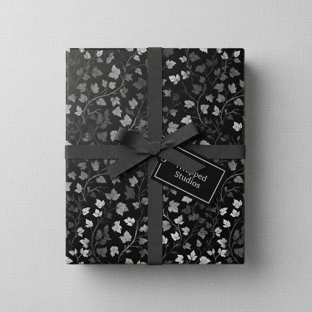 Elegant gift wrapped in black floral wrapping paper with gray ribbon and tag.