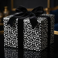 Modern black and white abstract leaf wrapping paper on an elegant gift box tied with a luxurious black velvet bow.
