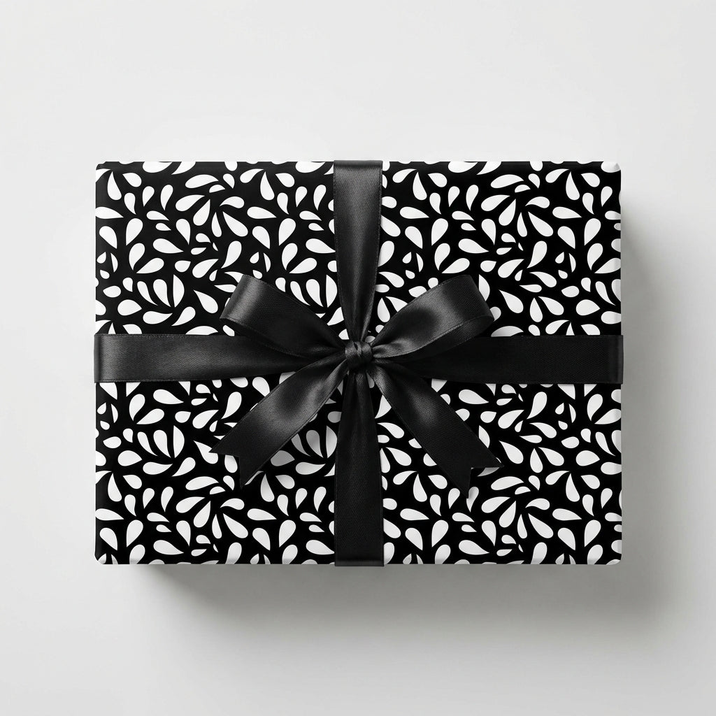 Elegant black and white wrapping paper with an abstract leaf pattern and a black satin bow on a rectangular gift box.