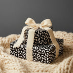 Luxury black and white abstract gift wrap on stacked boxes tied with a thick cream velvet ribbon.