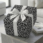 Elegant black and white wrapping paper featuring a modern abstract pattern, tied with a large white ribbon bow on a stylish gift box.