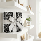 Luxury black and white abstract pattern wrapping paper with a large white bow, perfect for modern, elegant gifting.