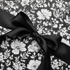Elegant floral wrapping paper in black and white, tied with a satin black ribbon.