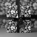 Elegant floral wrapping paper in black and white, tied with a black satin ribbon and gift tag.