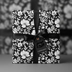 Elegant floral wrapping paper in black and white, tied with a black satin ribbon and gift tag.