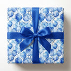 Square gift wrapped in blue balloon print wrapping paper with a satin ribbon bow.
