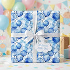 Blue balloon wrapping paper, tied with a white ribbon, perfect for a baby shower gift.