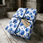 Blue balloon birthday wrapping paper on a gift tied with twine and a Cheers tag, by Wrapped Studios.