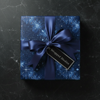 Navy blue floral wrapping paper on a square gift box with a satin ribbon and tag.