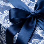 Elegant blue floral wrapping paper tied with a luxury navy satin bow by Wrapped Studios.