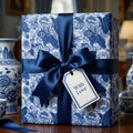 Luxury blue and white floral wrapping paper with a navy satin ribbon and gift tag by Wrapped Studios.