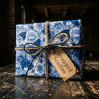 Blue and white vintage floral wrapping paper from Wrapped Studios, tied with twine on a rustic wooden table.