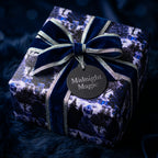 Elegant navy blue Christmas wrapping paper with winter forest design and velvet bow by Wrapped Studios.