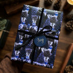 Luxury blue Christmas wrapping paper with winter forest design and black velvet bow by Wrapped Studios.