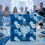 Elegant blue floral wrapping paper on a gift box with heart tag, perfect for wedding or special occasion presents.