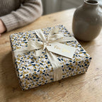 Luxury Wrapped Studios gift box with navy and gold terrazzo wrapping paper, cream ribbon, and a "For You" gift tag.