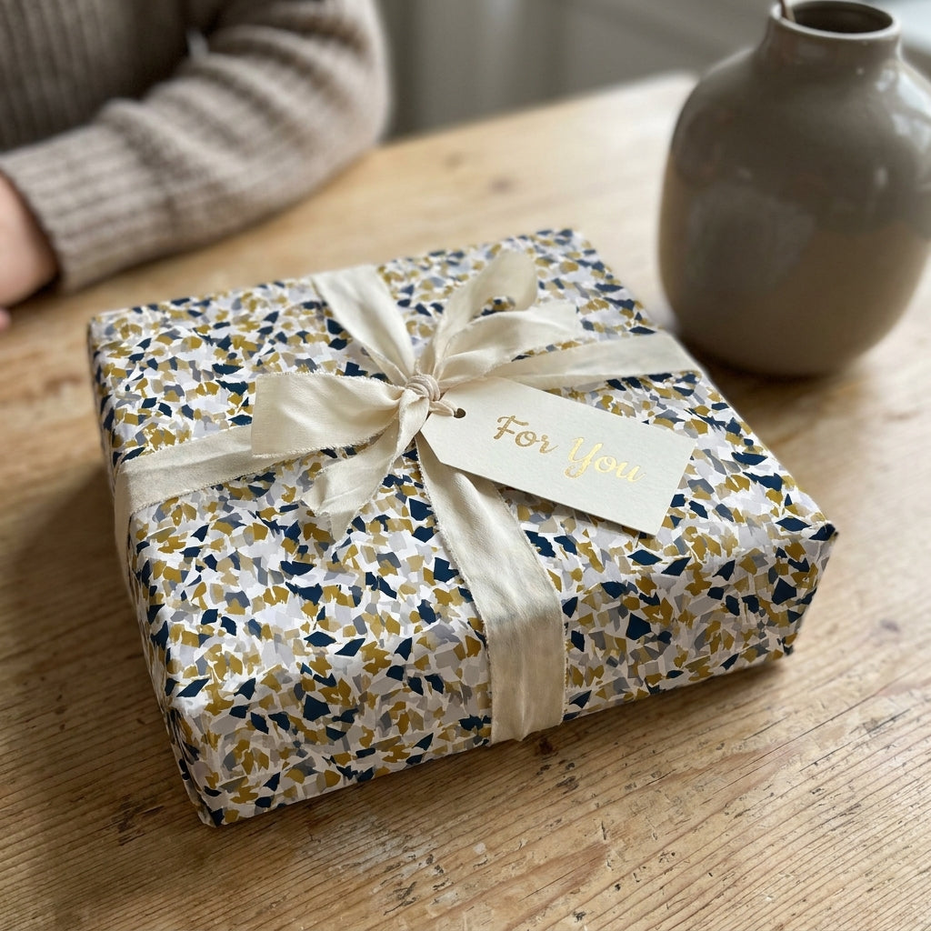 Luxury Wrapped Studios gift box with navy and gold terrazzo wrapping paper, cream ribbon, and a "For You" gift tag.