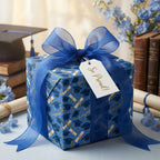 Blue graduation wrapping paper with mortarboards, sheer ribbon, and gift tag by Wrapped Studios.