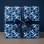 Blue graduation wrapping paper with caps and diplomas, tied with a navy satin bow by Wrapped Studios.