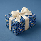 Blue graduation wrapping paper with cap and diploma pattern, tied with a cream ribbon by Wrapped Studios.