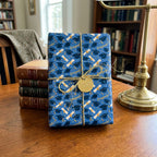 Blue graduation wrapping paper with caps and diplomas, tied with gold twine by Wrapped Studios.