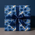 Blue and gold graduation wrapping paper with graduation caps and a navy satin ribbon by Wrapped Studios.