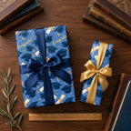 Blue graduation wrapping paper with caps and diplomas, featuring satin bows, by Wrapped Studios.
