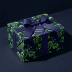 Luxury dark green botanical wrapping paper with a navy bow on a gift box by Wrapped Studios.