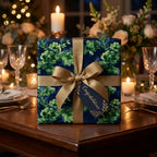 Navy and green floral wrapping paper with a gold ribbon on an elegant dinner table, by Wrapped Studios.