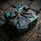 Luxury dark botanical wrapping paper with a charcoal bow and slate tag by Wrapped Studios.