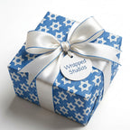 Blue Hanukkah wrapping paper with a Star of David pattern and luxury white ribbon by Wrapped Studios.