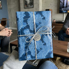 Blue city map wrapping paper with a silver ribbon and tag by Wrapped Studios.