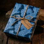 Blue map wrapping paper by Wrapped Studios on a gift box tied with twine and a Happy Travels tag.