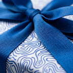 Luxury blue and white swirl wrapping paper with a dark blue ribbon bow, ideal for modern gift wrap on any occasion.