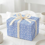 Elegant blue and white wavy pattern gift wrap with a cream ribbon bow, perfect for modern birthday or wedding presents.