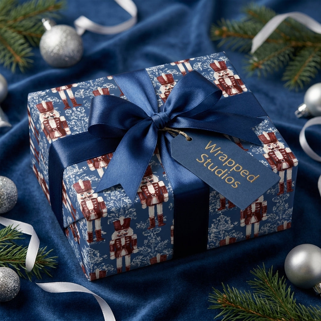 Navy blue nutcracker Christmas wrapping paper with a satin bow and tag by Wrapped Studios.