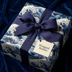 Elegant gift wrapped in blue wave pattern paper with a matching satin ribbon bow.