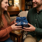 Passing a gift wrapped in Wrapped Studios floral wrapping paper with a navy ribbon.