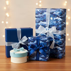 Elegant gifts wrapped in blue cloud-patterned wrapping paper with silver and blue satin ribbons for Christmas or birthdays.