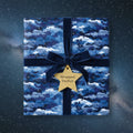 Elegant gift wrapped in blue cloud and star wrapping paper with velvet ribbon and gold star tag.
