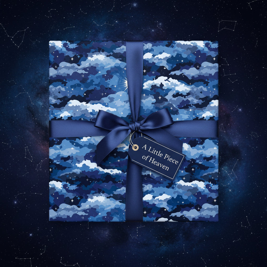 Square gift wrapped in navy star and cloud wrapping paper with a satin bow and tag on a space background.