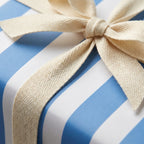 Blue striped wrapping paper with a cream cotton ribbon bow, elegant birthday gift wrap by Wrapped Studios.